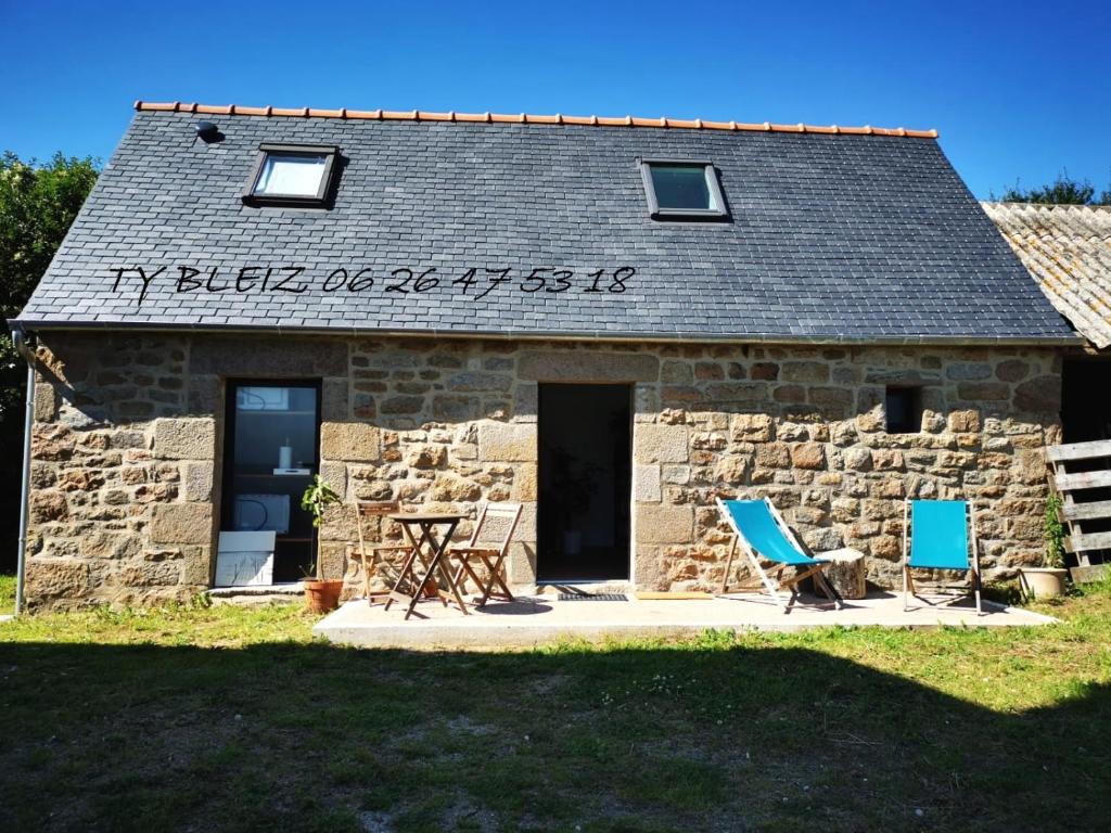 - un bâtiment en pierre avec deux chaises et une table dans l'établissement Ty Bleiz, charmante maison en pierre, 3kms plages, Trégastel, à Saint-Samson