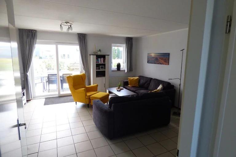 a living room with a black couch and a yellow chair at Ferienhaus Fridolin Fort Soleil 27, Breskens Zeeland in Breskens