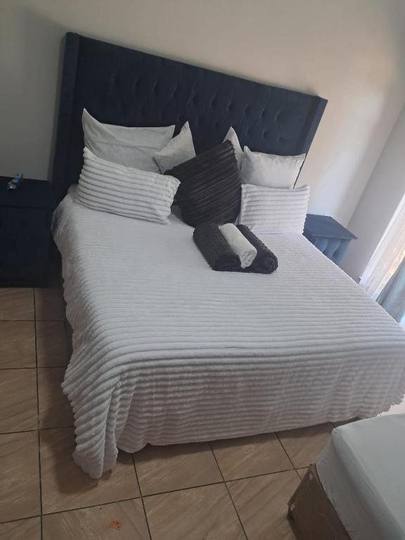 a large white bed with black and white sheets and pillows at Arcon Guest House in Vanderbijlpark
