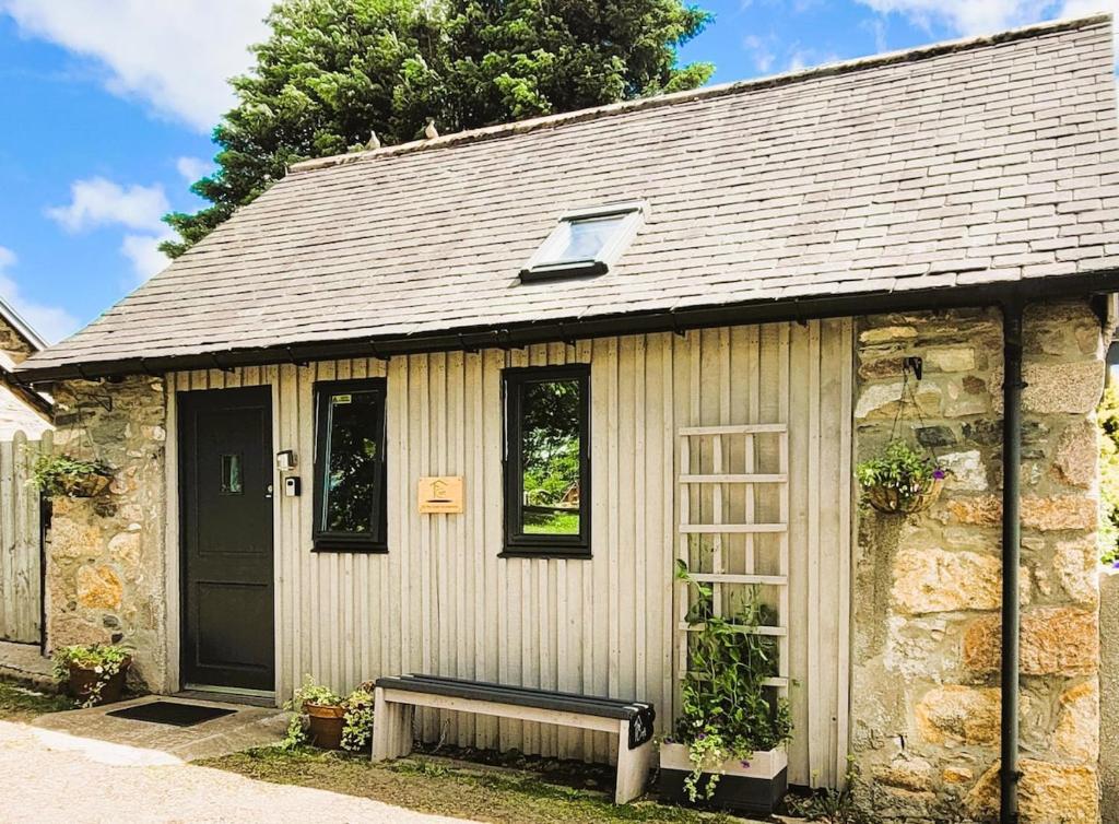 a stone house with a bench in front of it at Luxury Speyside Hideaway, Dog Friendly, Malt Whisky Trail, Village Green in Archiestown