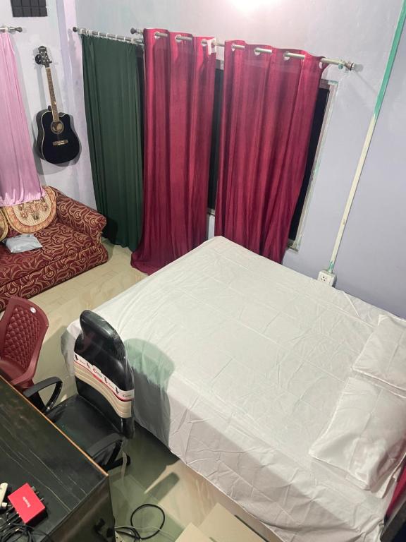 una camera con letto e tende rosse di Mini Sweet Haven a Digboi