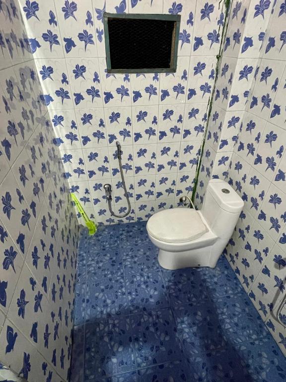 bagno con servizi igienici e piastrelle bianche e blu di Mini Sweet Haven a Digboi