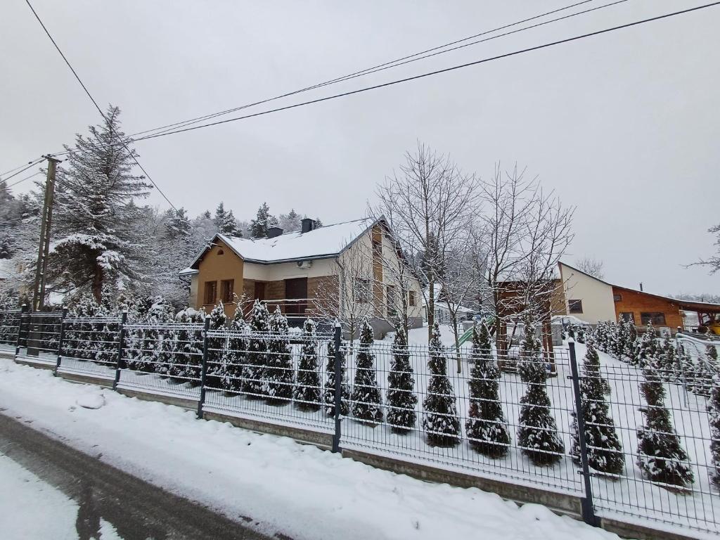 a fence covered in snow in front of a house at Agroturystyka Noclegi Podlesie in Gorlice