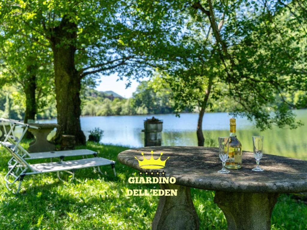 una mesa de piedra con dos vasos y una botella de alcohol en Vista Lago-Appartamento Giardino dell'Eden, en Ghirla