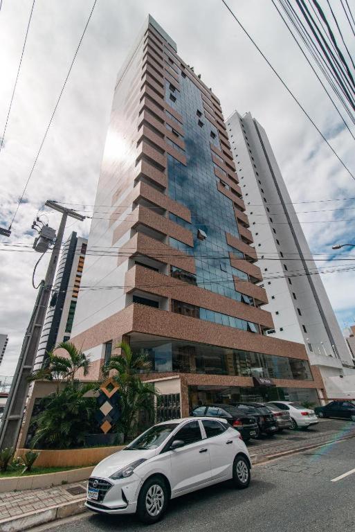 a white car parked in front of a tall building at Gold flat Manaíra 602 in João Pessoa