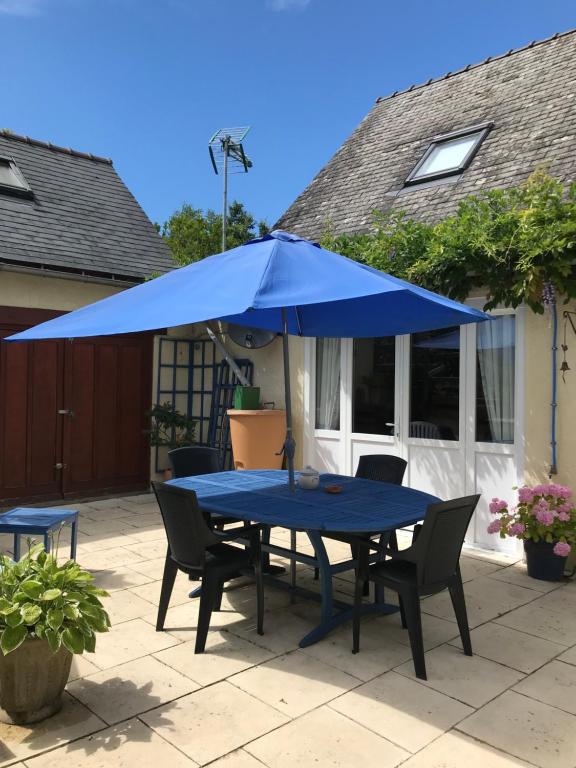un tavolo blu e sedie sotto un ombrellone blu di Cottage Les Glycines a Javron-Les-Chapelles