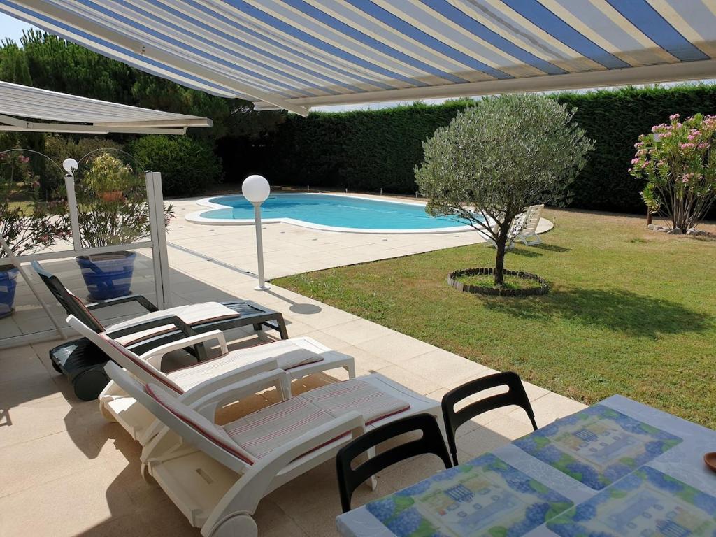 un patio avec une table et des chaises et une piscine dans l'établissement Studio meublé 2 pièces jardin piscine, à Soulac-sur-Mer