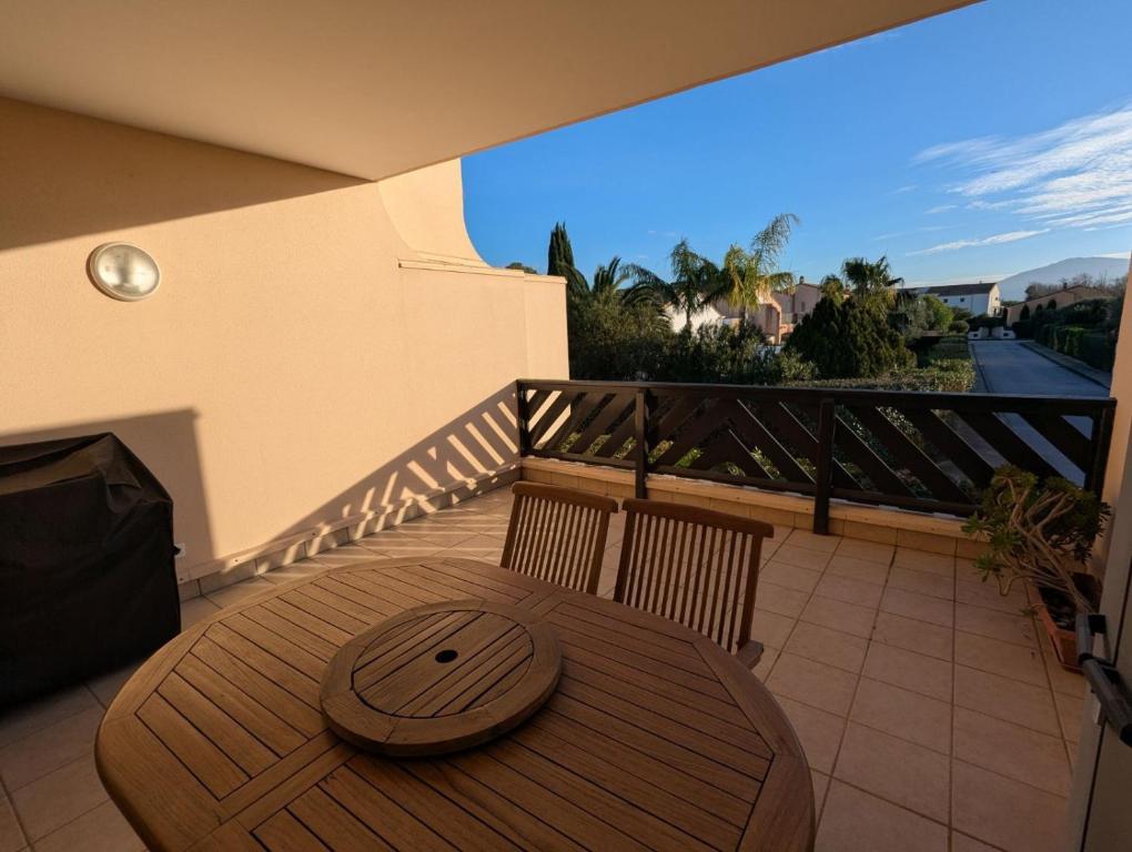 une table et des chaises en bois sur un balcon dans l'établissement APPARTEMENT T3 AVEC TERRASSES et PISCINE SAINT CYPRIEN, à Saint-Cyprien