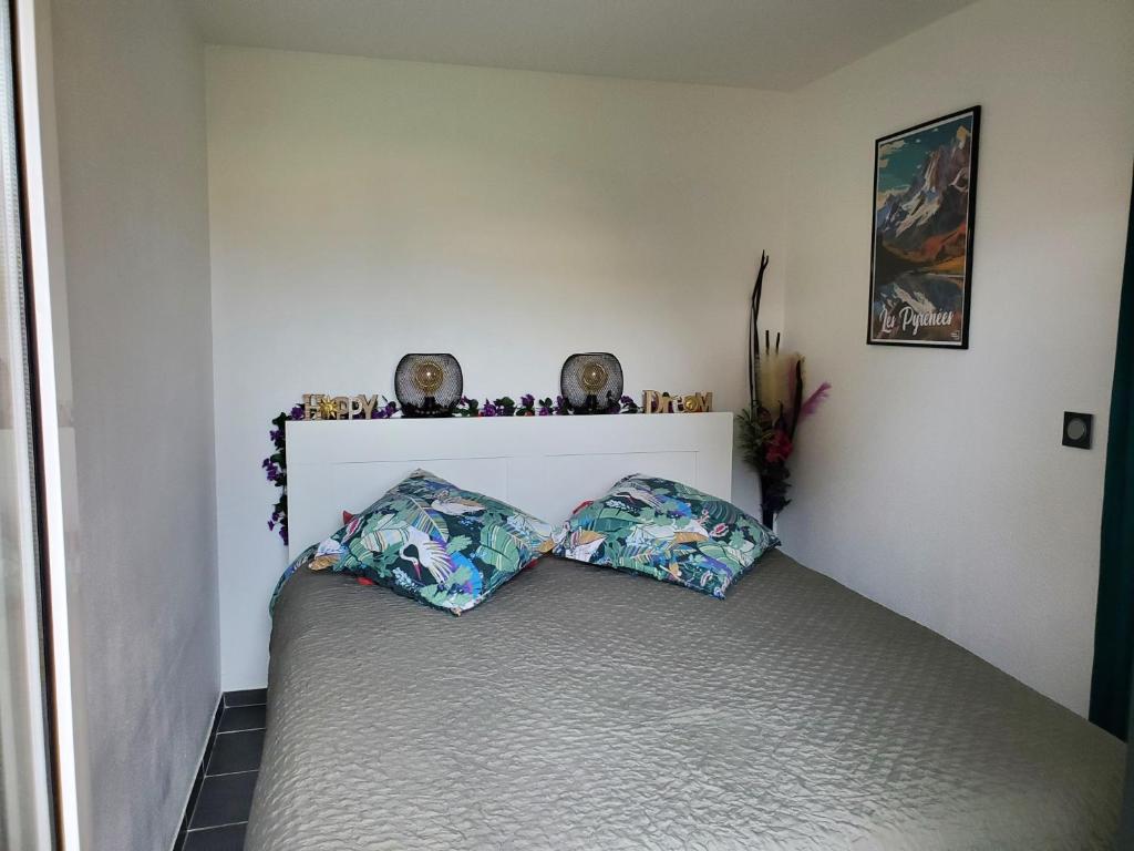 een slaapkamer met een bed met twee kussens erop bij APPT Cosy entier avec piscine in Toulouse