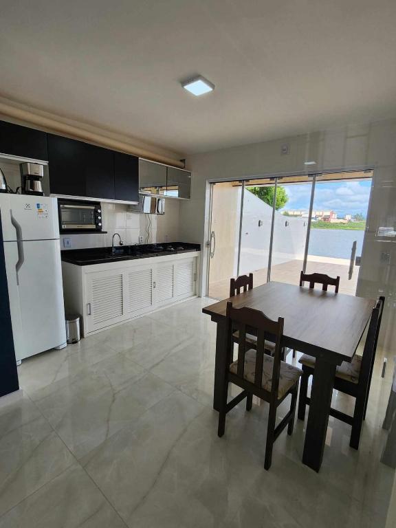a kitchen with a table and chairs and a view of the ocean at Apartamento-3 pé na areia, churrasqueira, acesso a lagoa, vista para rio, Torres e serra gaúcha in Passo de Torres