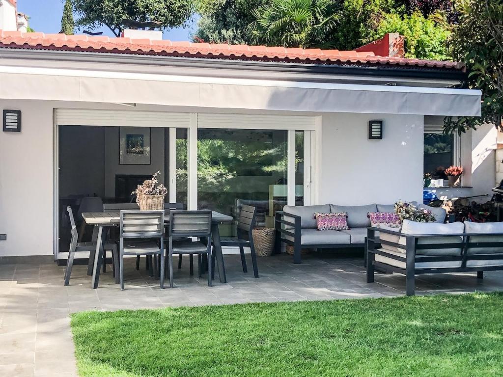 eine Terrasse mit einem Tisch, Stühlen und einem Sofa in der Unterkunft La Casa de la Sierra de Madrid in Hoyo de Manzanares
