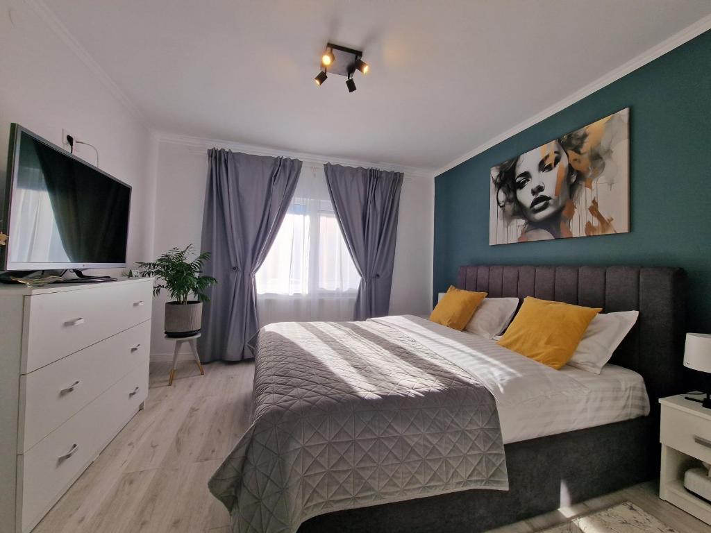 1 dormitorio con 1 cama con paredes azules y TV en Elite Apartment Onesti, en Onești