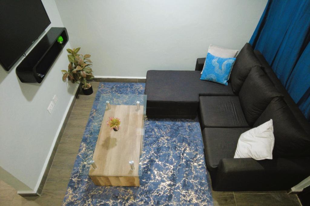 a living room with a black couch and a table at The Plan Budget Apartment Borteyman Accra in Accra