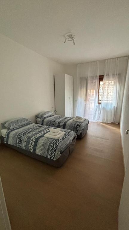 dwa łóżka ustawione w pokoju z oknem w obiekcie LA CASA DI ALICE 2 w mieście Lido di Ostia