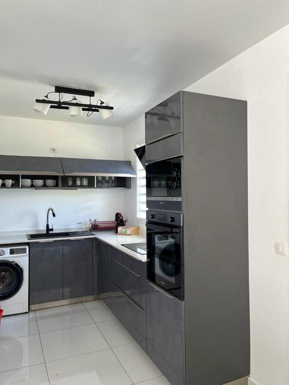a kitchen with stainless steel appliances and a sink at Location Villa Saint-François in Saint-François