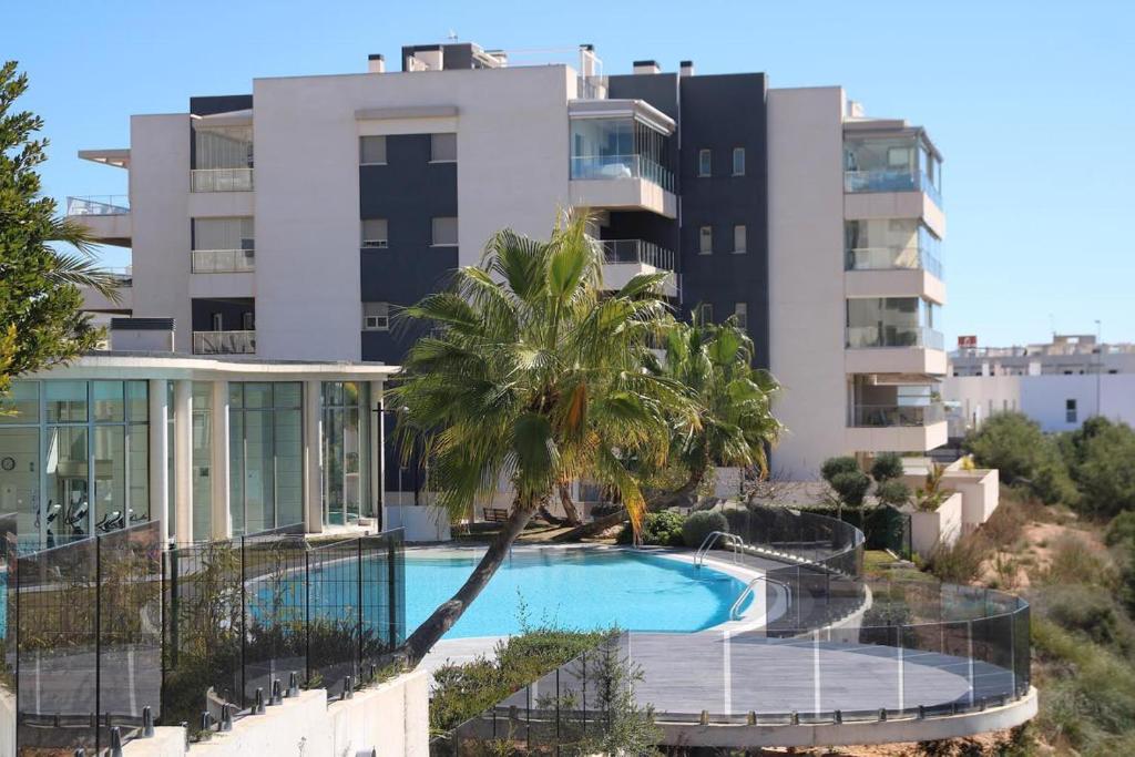 un immeuble avec une piscine et un palmier dans l'établissement 5-Star Complex With 3 Pools & Gym, à Orihuela Costa