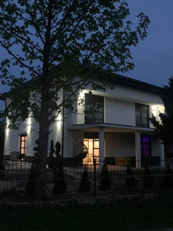 a white house with a tree in front of it at Ostoja Bachus in Sawin