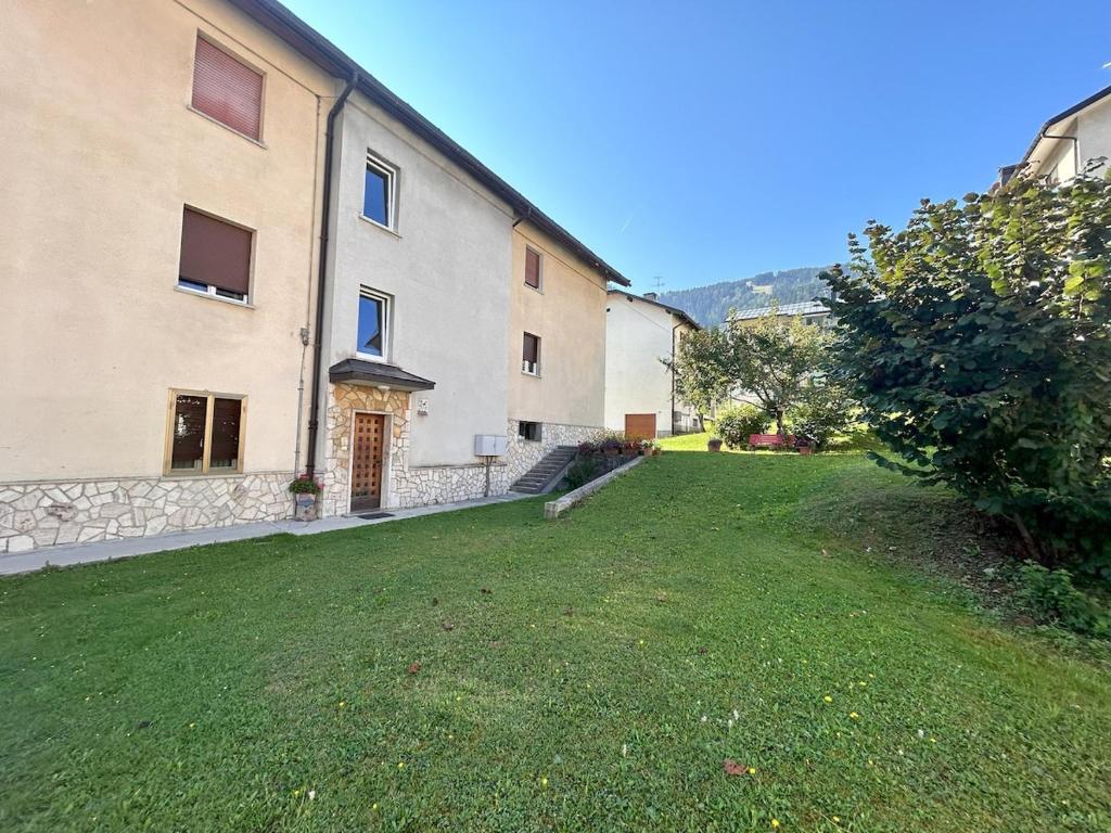 a large building with a grassy yard in front of it at Nandi-HolidaySport&Relax-Apt in Tarvisio
