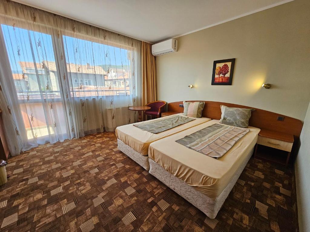 a hotel room with a bed and a large window at Family Hotel Jeri in Velingrad