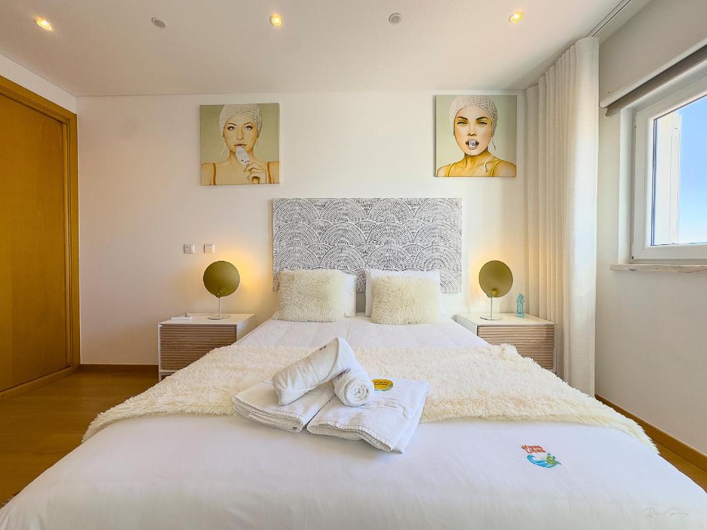 a bedroom with a large white bed with towels on it at Vibing & Liming Ericeira in Ericeira