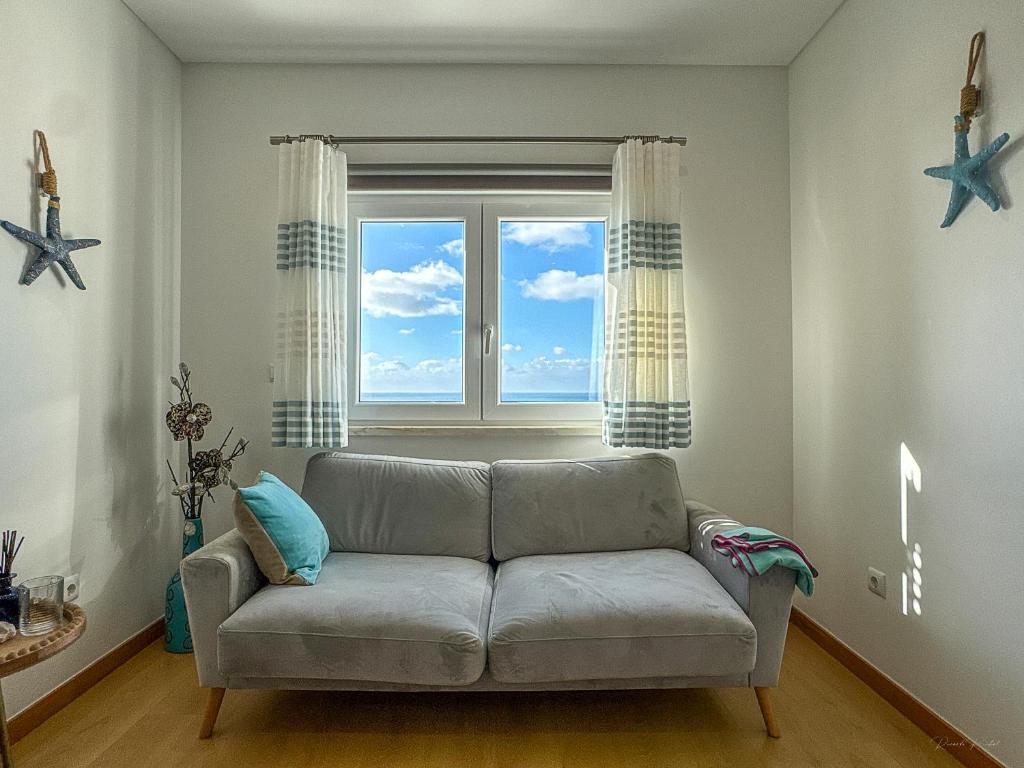 a living room with a couch and a window at Vibing & Liming Ericeira in Ericeira
