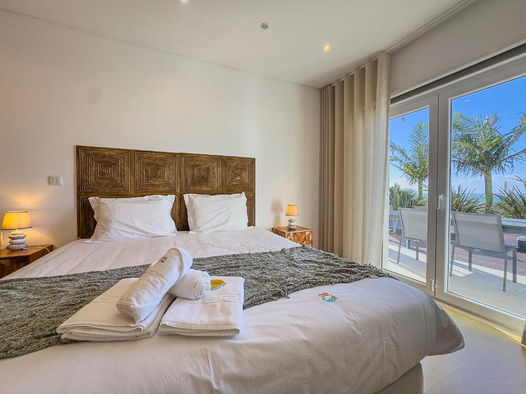 a bedroom with a large bed with towels on it at Vibing & Liming Ericeira in Ericeira