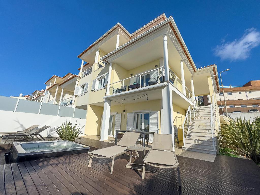 a house with two chairs and a table on a deck at Vibing & Liming Ericeira in Ericeira