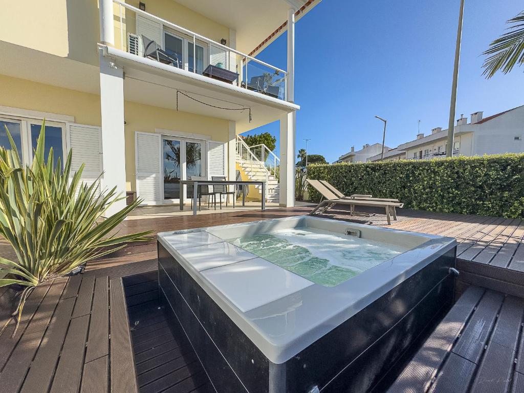 a hot tub on a deck in front of a house at Vibing & Liming Ericeira in Ericeira
