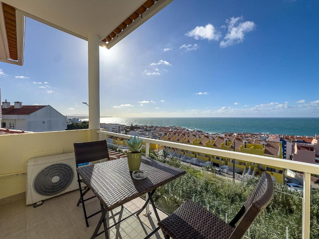 a balcony with a table and chairs and the ocean at Vibing & Liming Ericeira in Ericeira