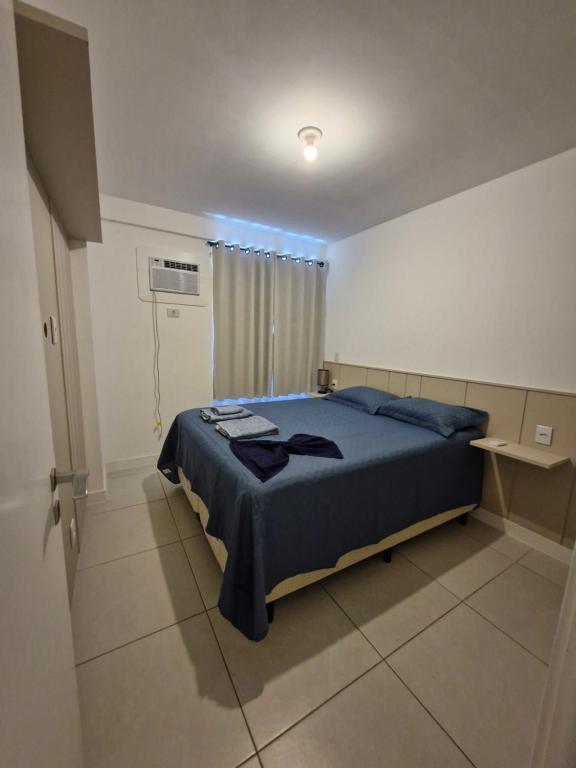a bedroom with a bed with a blue comforter at Studio Premium com Piscina e Vista próximo Pelinca in Campos dos Goytacazes