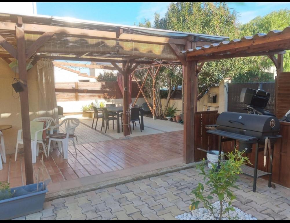 eine hölzerne Pergola mit einem Tisch und einem Grill in der Unterkunft Maison entre mer et montagne in Pollestres