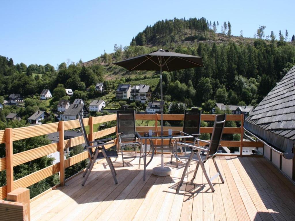 a deck with a table and chairs and an umbrella at Ferienhaus in Willingen mit eigenem Garten in Willingen