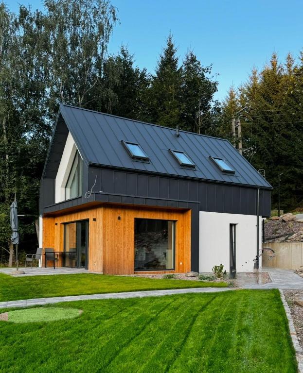 a house with a black roof and a green yard at Domki na Stronie C in Stronie Śląskie
