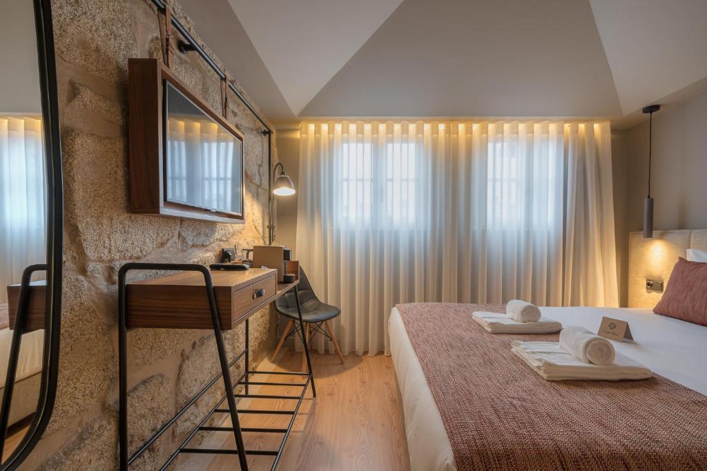 a hotel room with a bed and a desk with towels at Carpe Diem Porto By Dualhotels in Porto