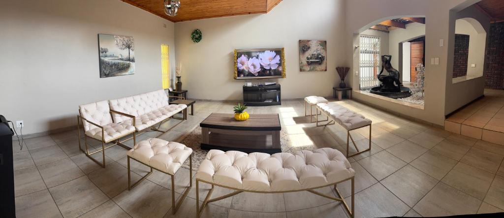 sala de estar con sillas blancas y TV de pantalla plana en Hendrinas Guesthouse, en Hendrina