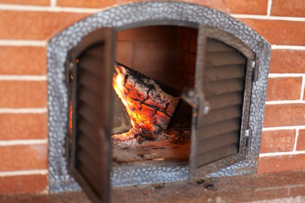 a brick oven with a fire inside of it at Casutele dintre brazi in Coverca