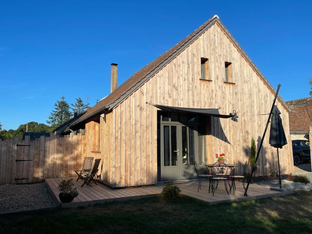 une grange avec une table et des chaises sur une terrasse dans l'établissement Gîte Ancien Atelier - chemin de halage, à Muides-sur-Loire