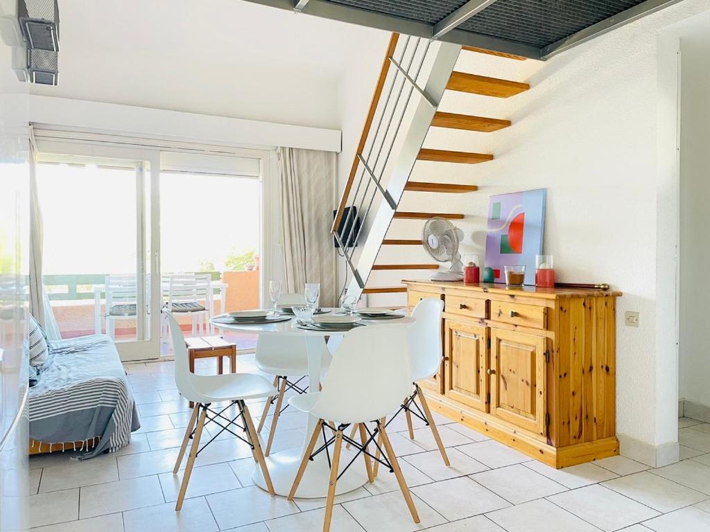 une salle à manger avec une table et des chaises blanches dans l'établissement Appart rénové - 4 personnes - piscine - parking, à Fitou