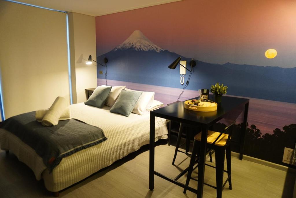 サンティアゴにあるDepartamento full equipado a pasos del movistar arena, moderno y cómodo con toda la magia del surのベッドルーム1室(ベッド1台、山の壁画のあるデスク付)