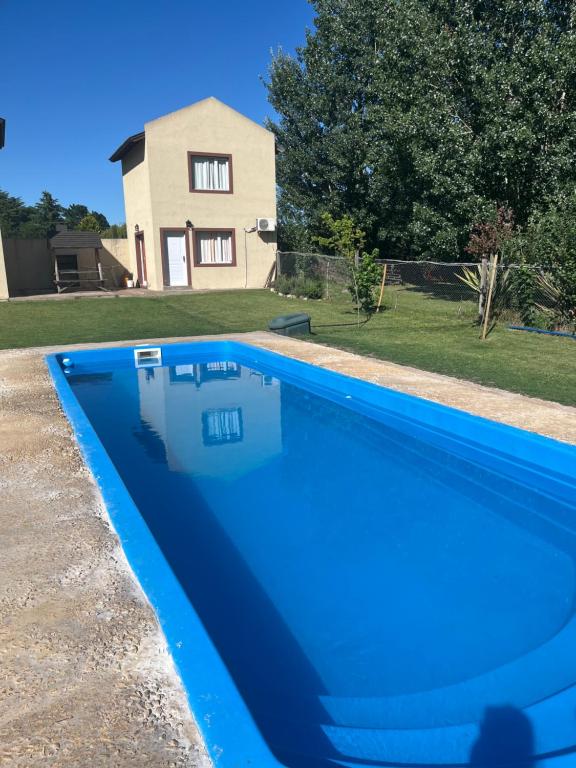 a blue swimming pool with a house in the background at Cabañas amaia in Tandil