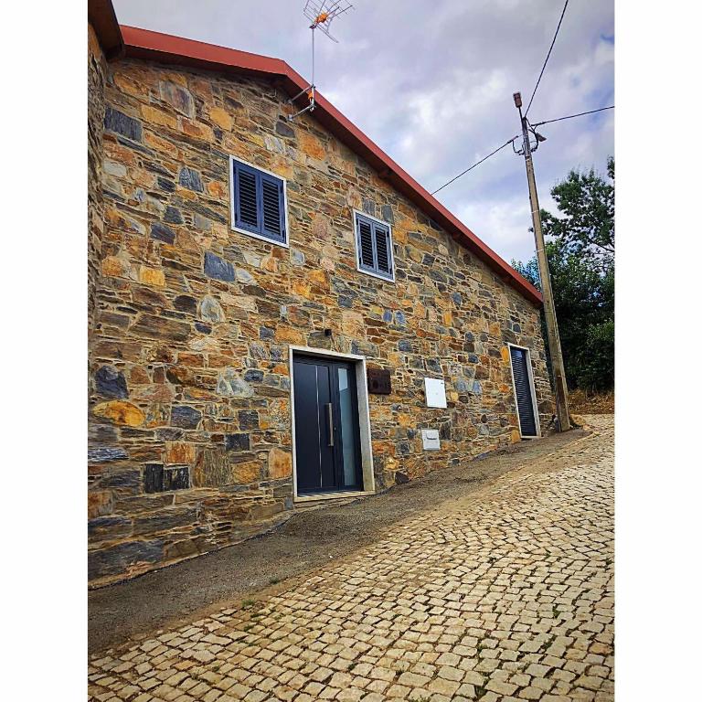 a stone building with a door on a cobblestone street at Casa do Henrique in Bragança