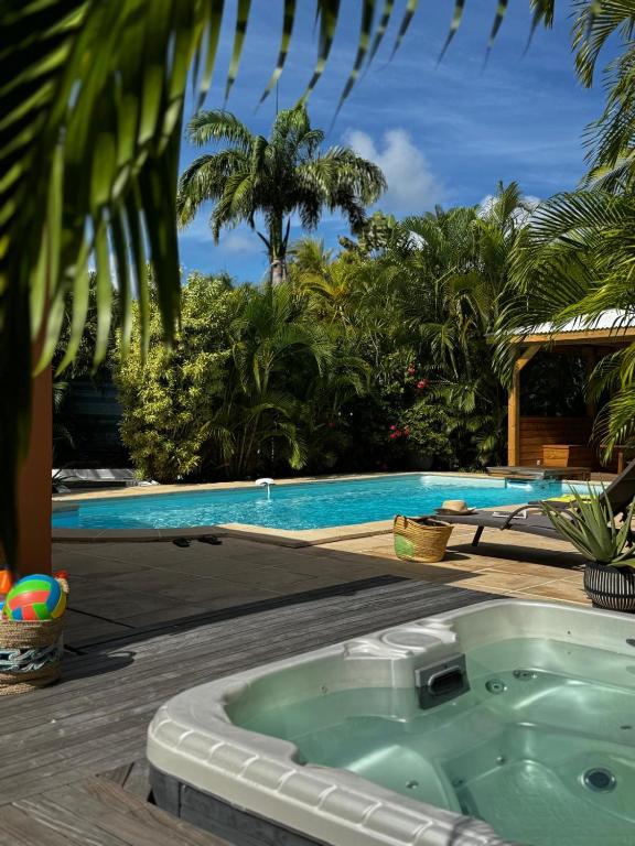 a bath tub sitting next to a swimming pool at Villa Douceur & Spa Piscine & Jacuzzi privés - proche plage in Saint-François