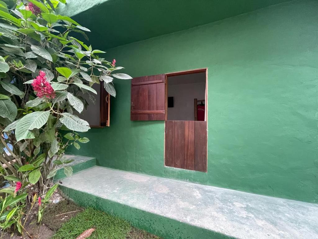 un edificio verde con una puerta y algunas flores en Vila 34, en Porto Seguro