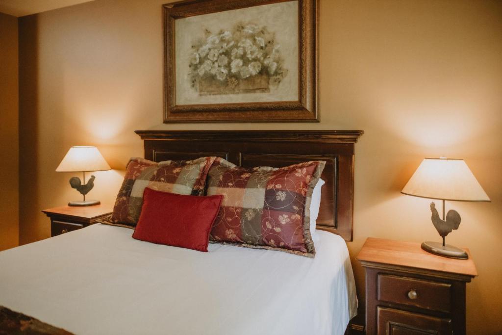 a bedroom with a bed with two lamps and a painting at Auberge du Lac Morency in Saint-Hippolyte