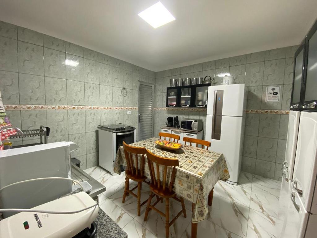 a kitchen with a table and a white refrigerator at Casa simples e aconchegante in Bertioga