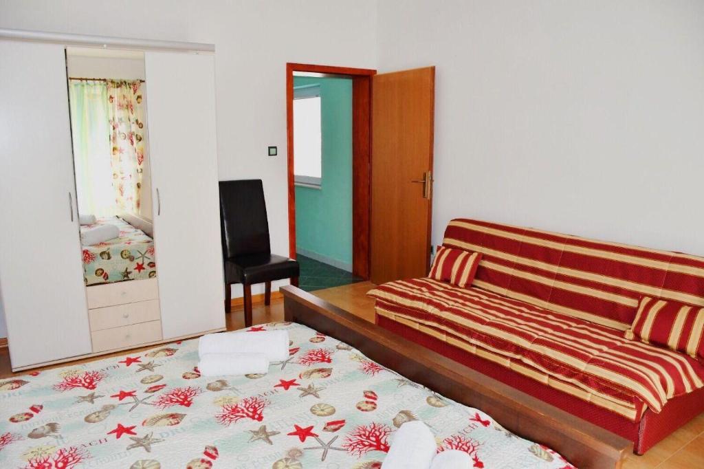 sypialnia z łóżkiem, kanapą i lustrem w obiekcie Apartments Darko w Sukošanie
