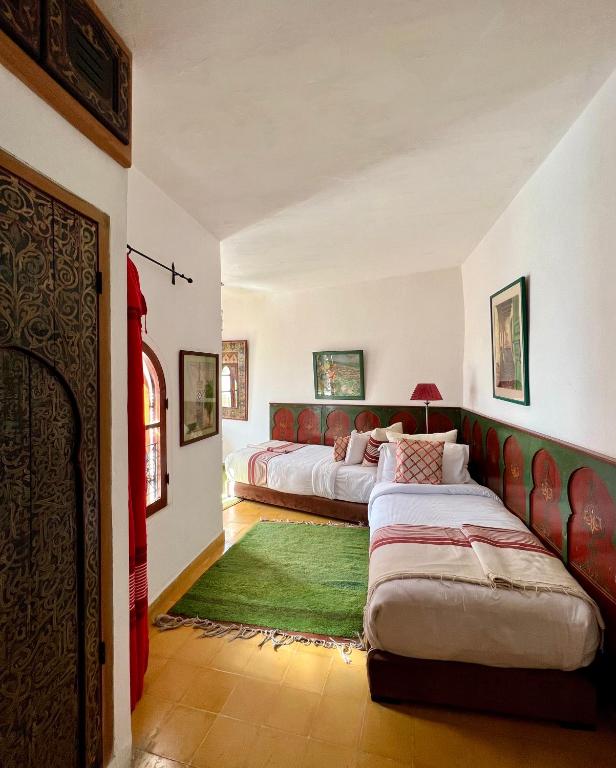 a bedroom with two beds and a green rug at RIAD OASIS D'ASILAH in Asilah
