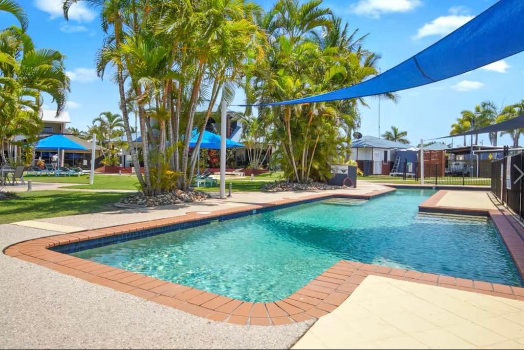 a swimming pool in a resort with palm trees at Pool Side Holiday Home in Agnes Water