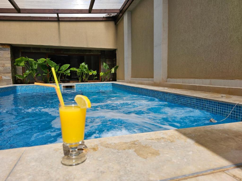 a glass of orange juice sitting next to a swimming pool at Family Hotel Jeri in Velingrad