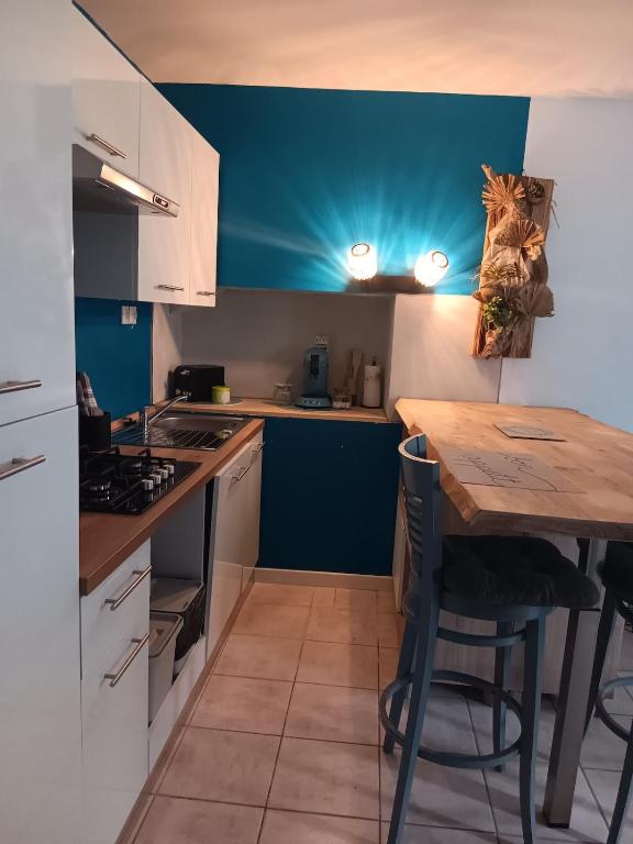 une cuisine avec une table en bois et un mur bleu dans l'établissement Le Nid Breton, à Pléhédel